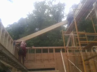 Carpenter raising a rafter beam on a new second story frame in Arlington