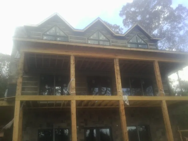 Dormers and porch framing on a large log home under construction — Roof Coating work by our crew in Arlington